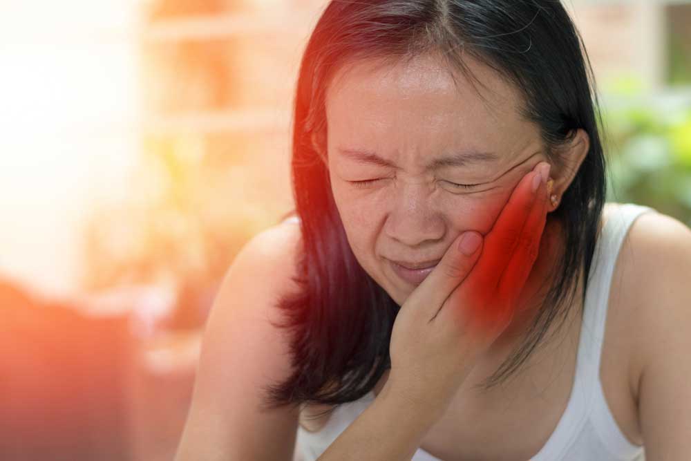 a dental patient holding her jaw in pain