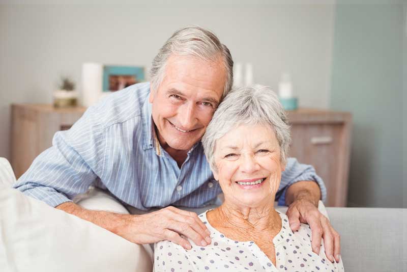an elderly couple smiling with their new dental implants