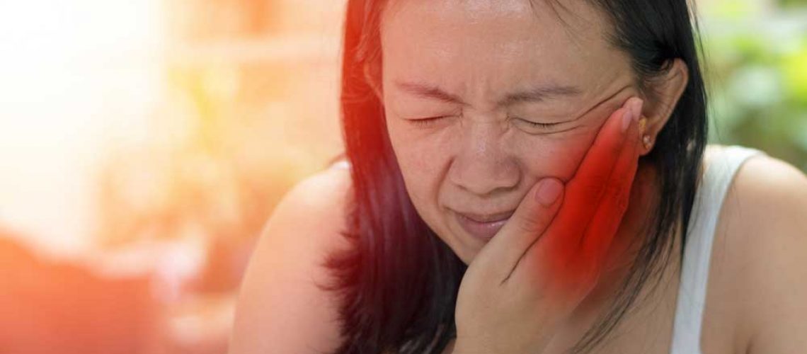 a dental patient holding her jaw in pain